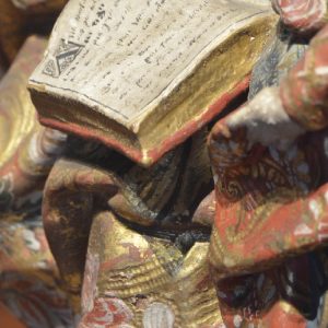 Livro. Pormenor da escultura em madeia policromada 'São Joaquim, Santa Ana e a Virgem Maria'. Século XVIII.