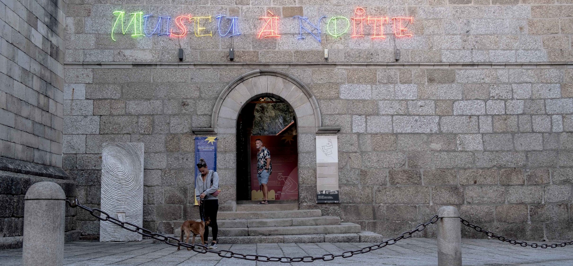 Entrada lateral do Museu Alberto Sampaio. Portal de ferro forjado com as letras 'Museu à Noite'.